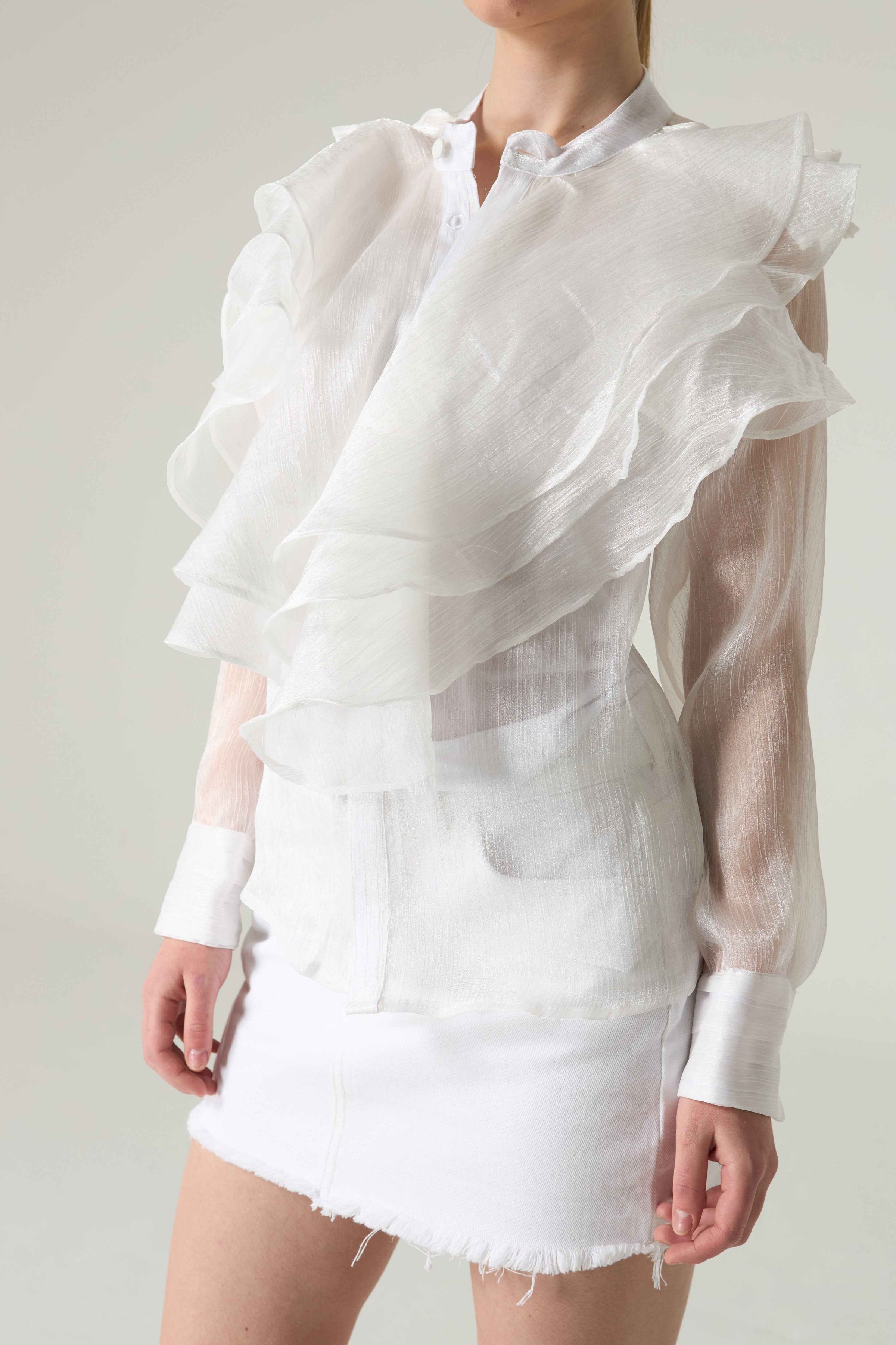 White ruffled blouse and skirt set on a plain background.