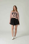 Woman wearing a pink 'NYC' sweatshirt and black skirt on a white background.