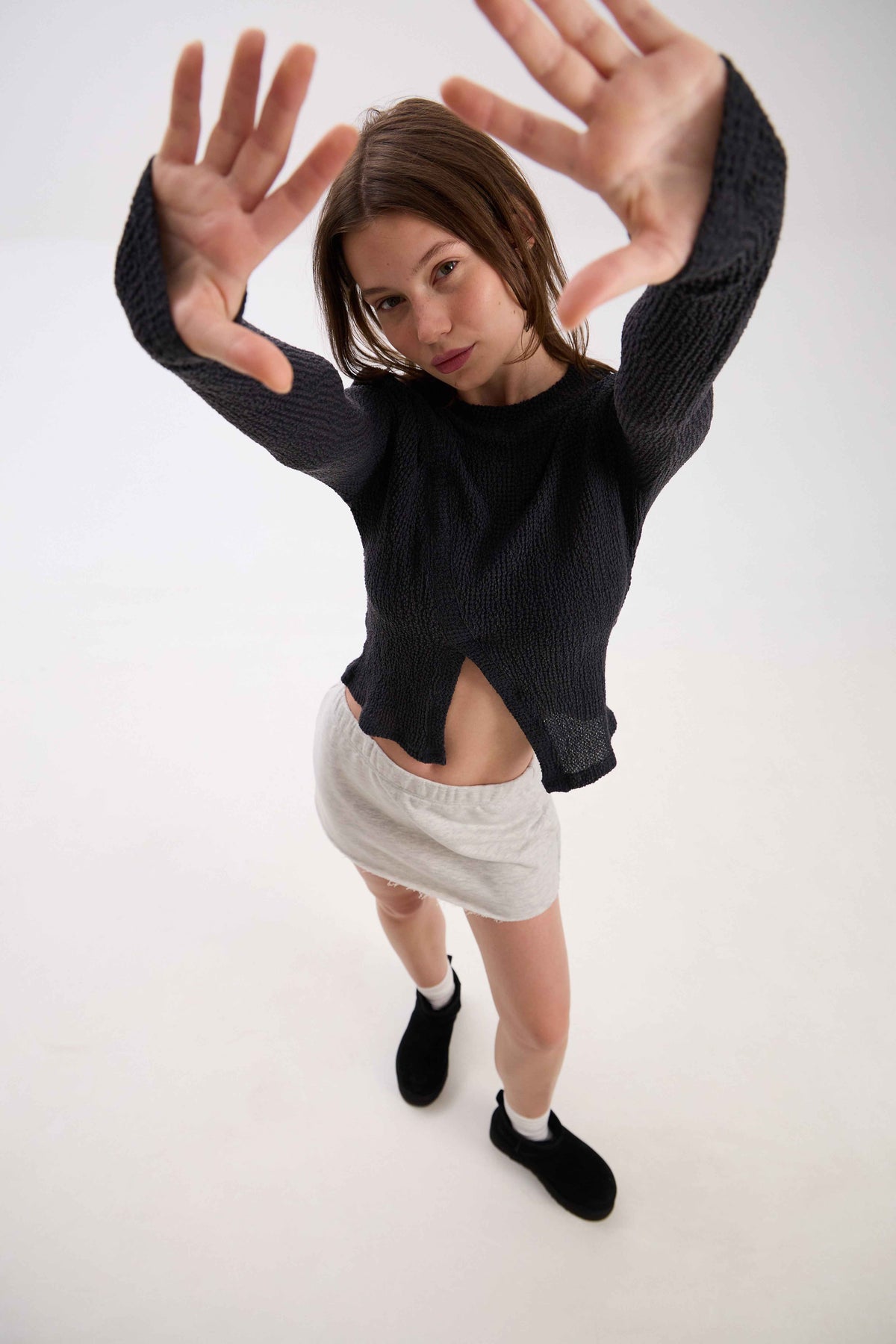 Person wearing a black sweater and white skirt on a white background.