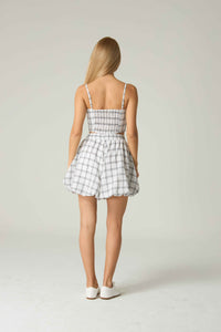 Woman wearing a checkered dress on a plain background.