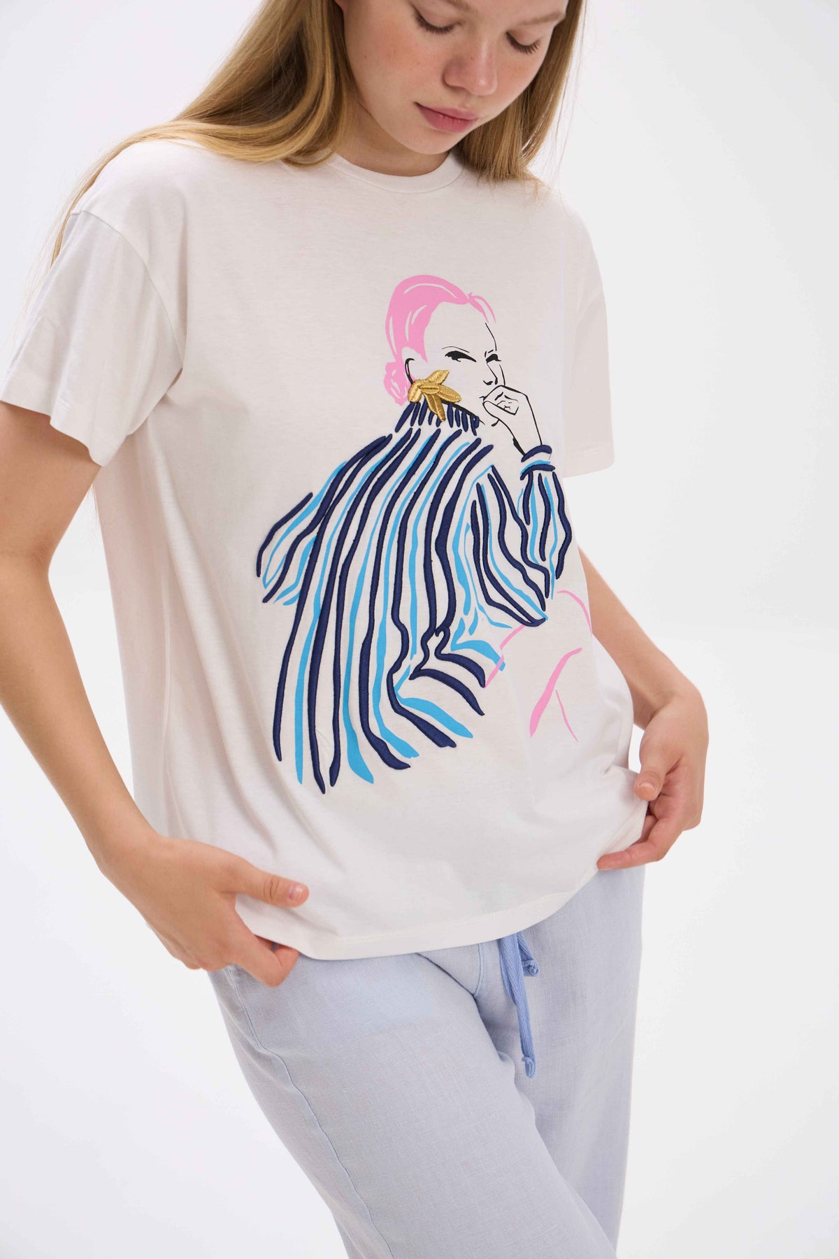 Person wearing a white t-shirt with a colorful graphic design on a plain background.