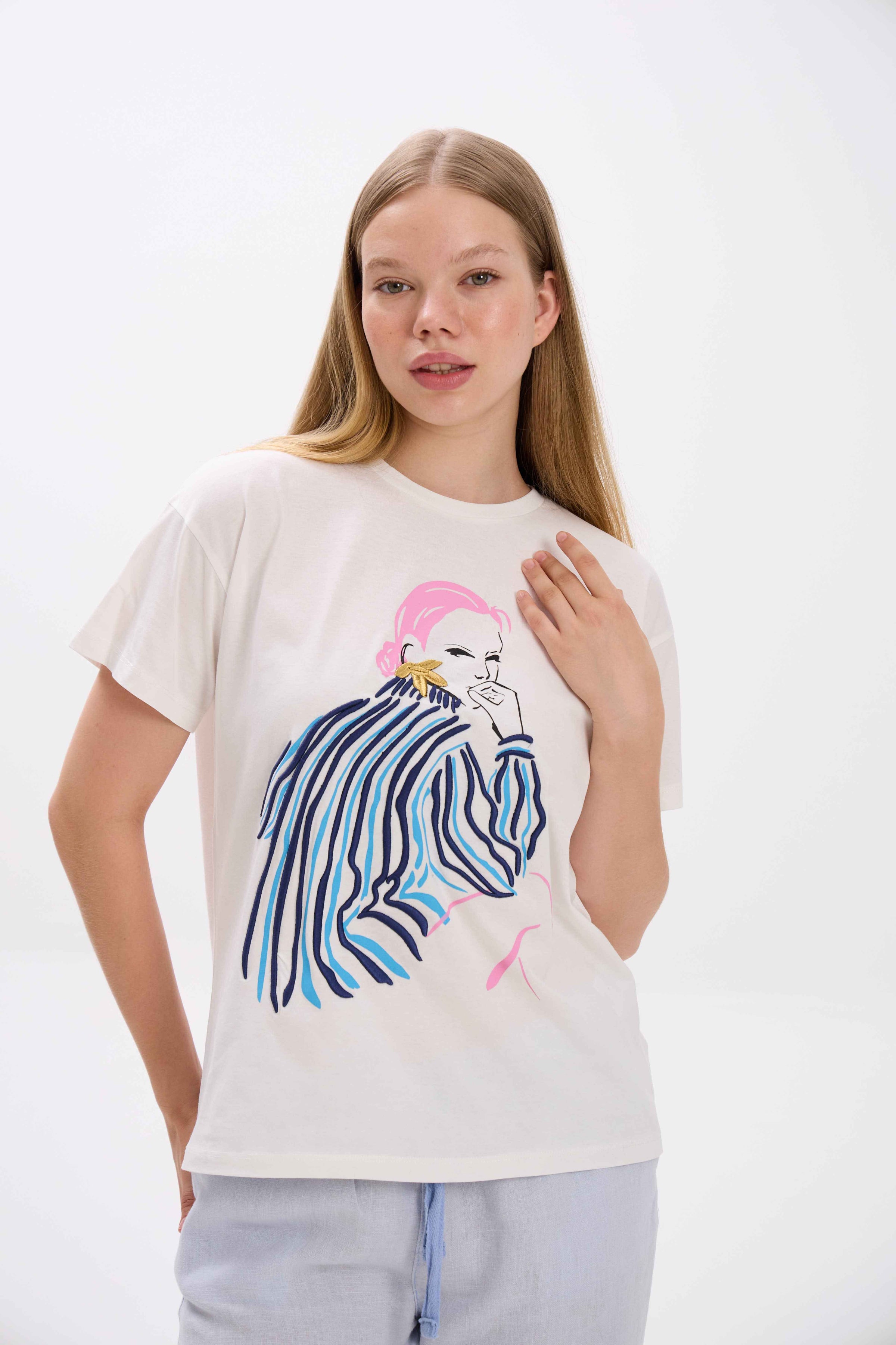 Woman wearing a white t-shirt with a graphic design on a plain background.