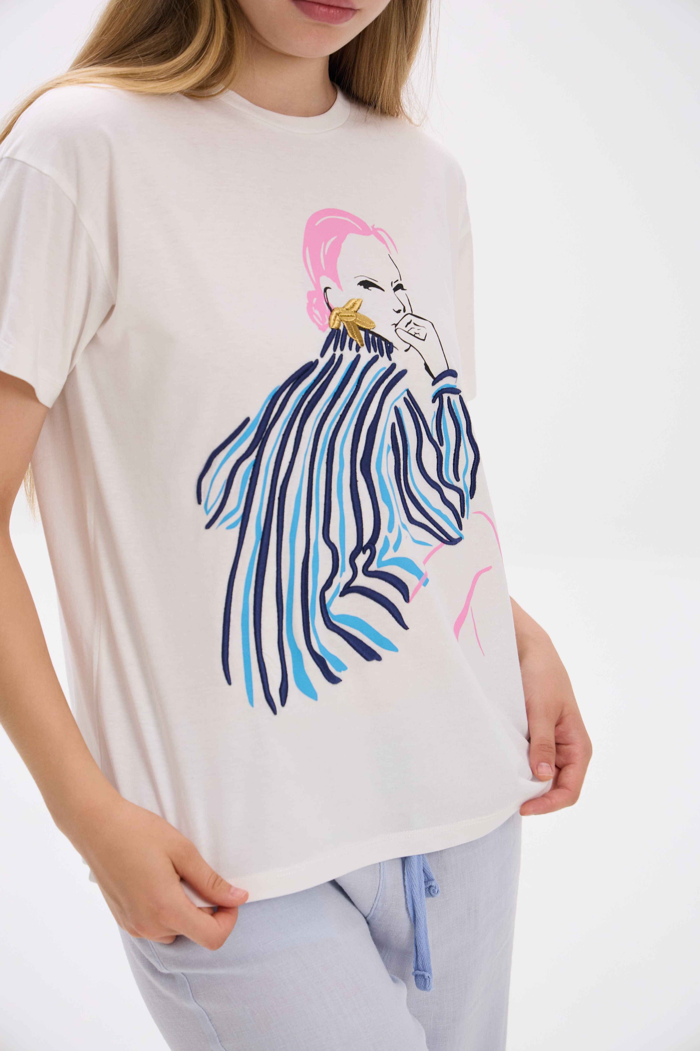 Person wearing a white t-shirt with a colorful zebra design on a plain background.