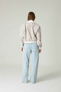 Person wearing a light-colored sweater and light blue pants on a white background.