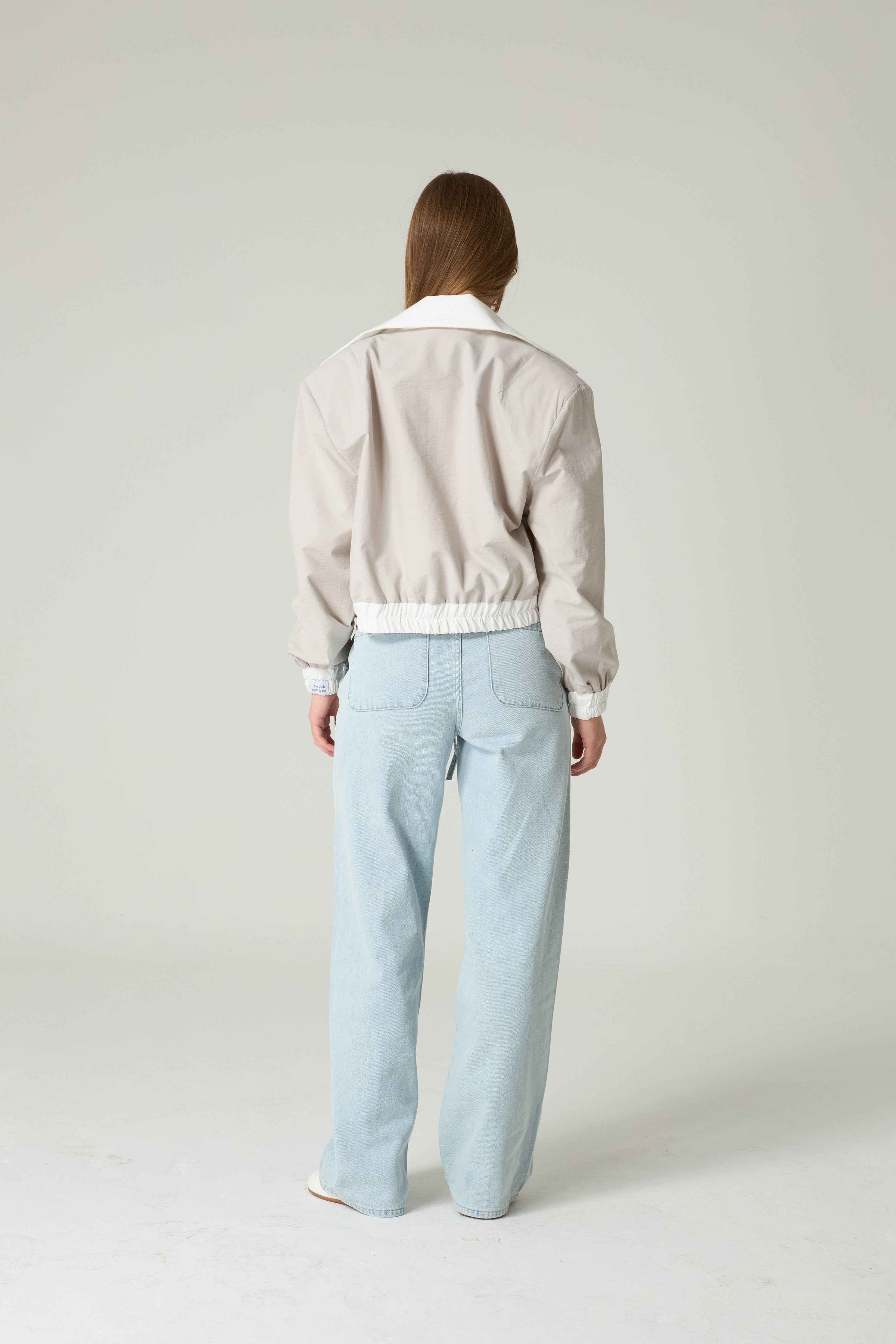 Person wearing a light-colored sweater and light blue pants on a white background.