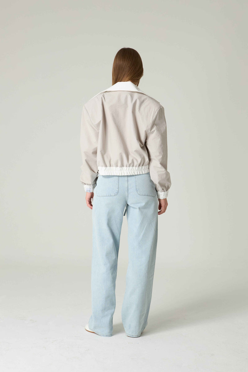 Person wearing a light-colored sweater and light blue pants on a white background.