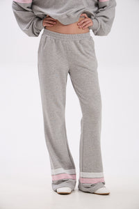 Person wearing gray sweatpants with pink accents on a white background.