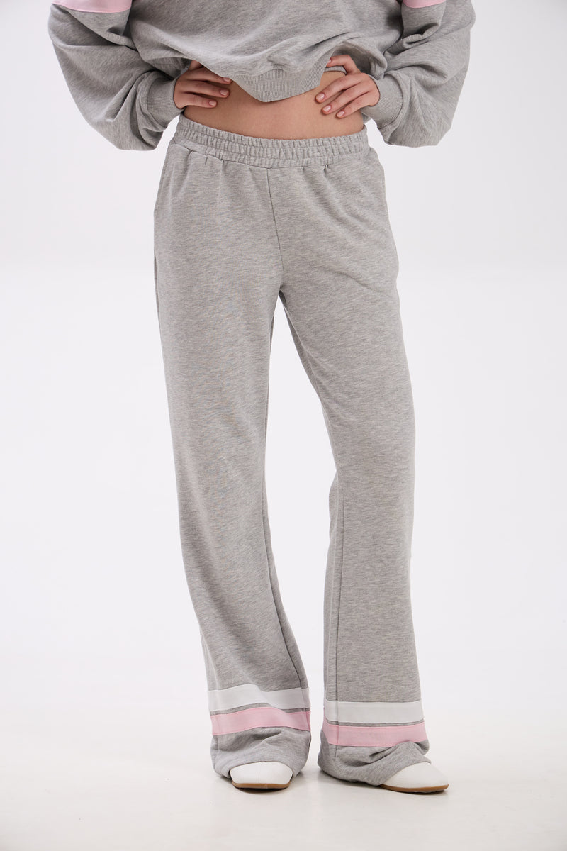 Person wearing gray sweatpants with pink accents on a white background.