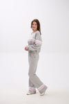 Person wearing a gray tracksuit with pink accents on a white background.