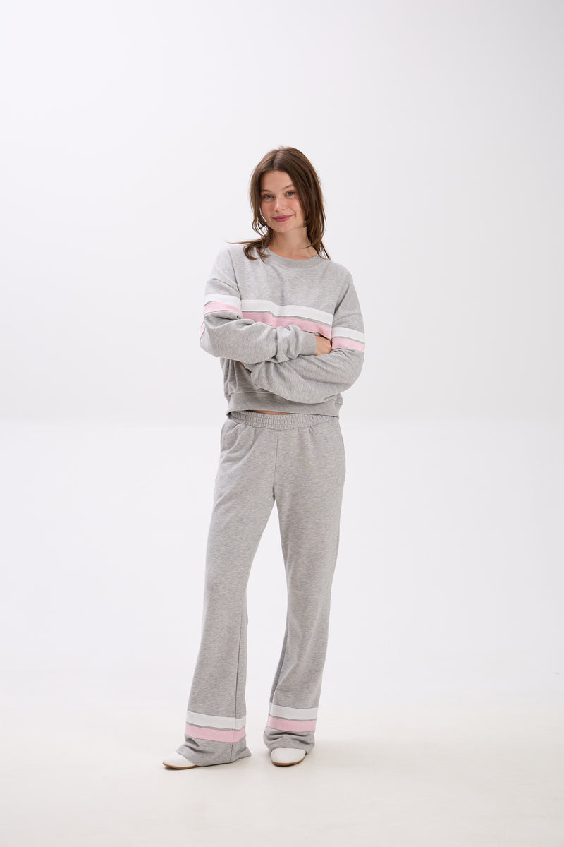 Person wearing a gray tracksuit with pink accents on a white background.
