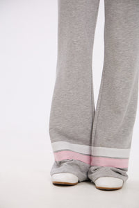 Gray sweatpants with pink accents worn by a person on a white background.