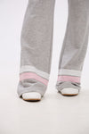 Gray sweatpants with pink bands worn by a person on a white background.