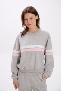 Woman wearing a gray sweatshirt with pink and white stripes on a white background.