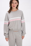 Woman wearing a gray sweatshirt with pink and white stripes on a white background.