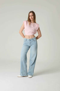 Woman wearing a pink top and light blue jeans on a plain background.