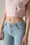 Person wearing a pink crop top and light blue jeans against a neutral background.