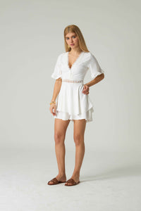 Woman wearing a white dress against a plain background.