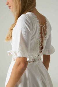 White lace dress with a plain background.