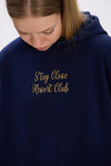 Close-up of navy blue hoodie featuring gold embroidered text “Stay Close Resort Club” on the chest.