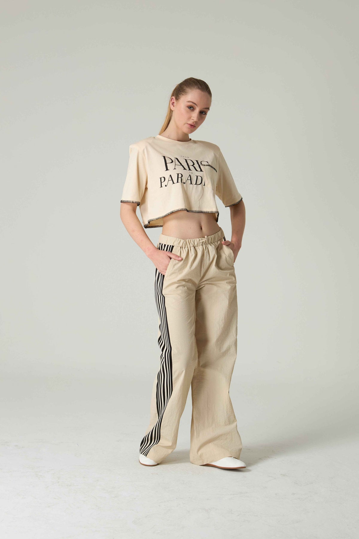 Woman wearing a beige 'Paris Parade' crop top and wide-leg pants on a plain background.