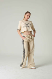 Woman wearing a beige 'Paris Parade' crop top and wide-leg pants on a plain background.