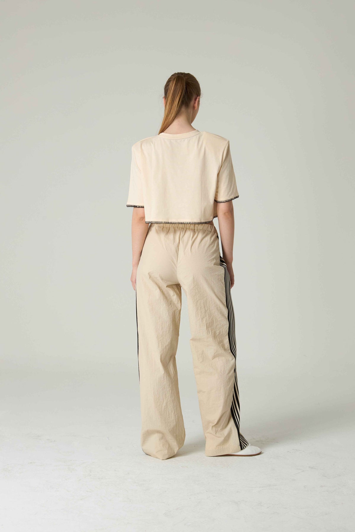 Person wearing a beige outfit with a plain background.