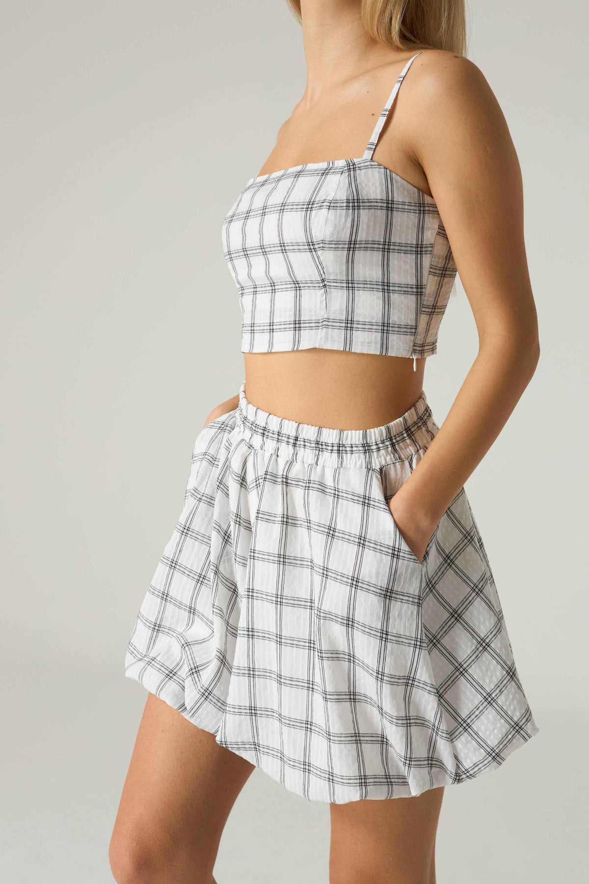 Person wearing a plaid two-piece outfit on a plain background.