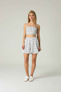 Woman wearing a checkered top and shorts set on a plain background.