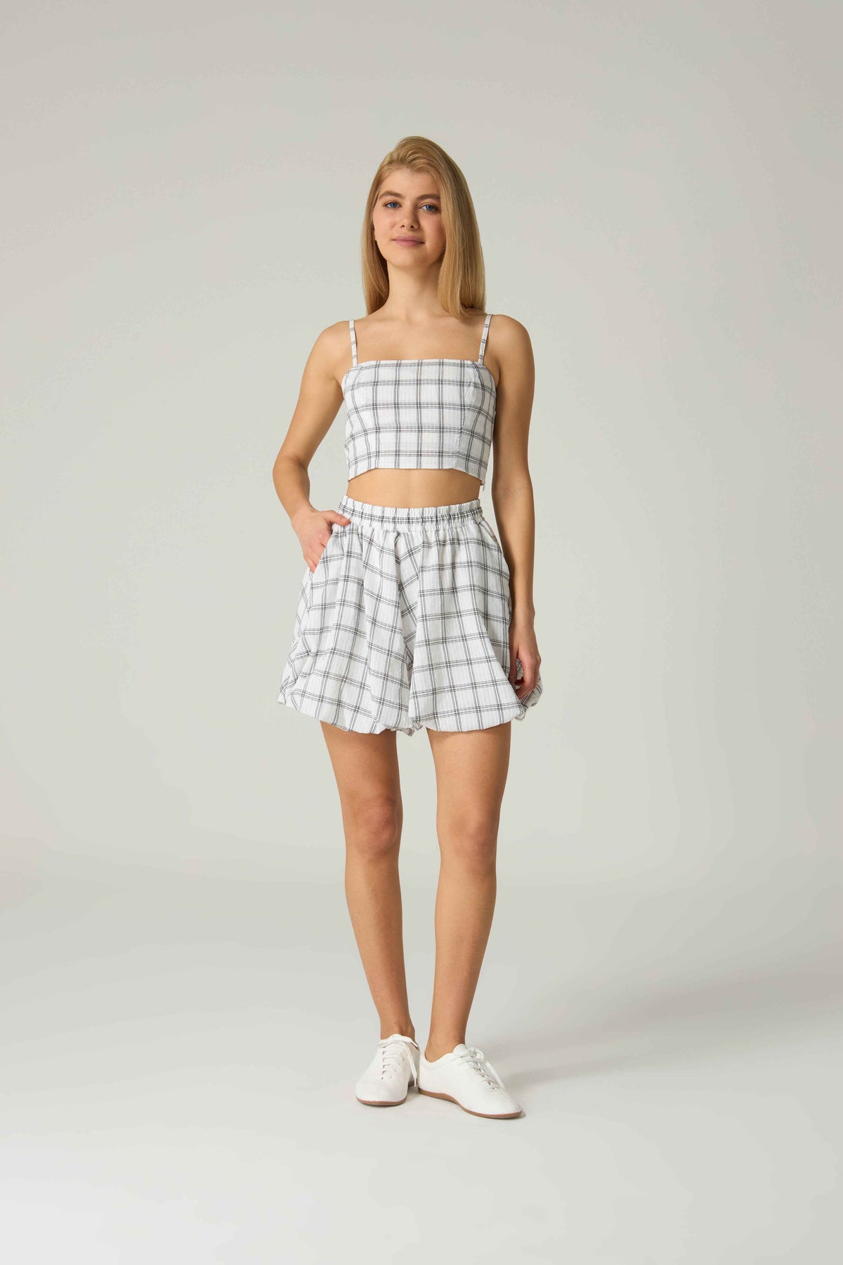 Woman wearing a checkered outfit with a top and shorts on a plain background.