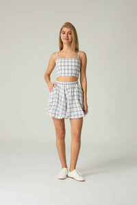 Woman wearing a checkered outfit with a top and shorts on a plain background.