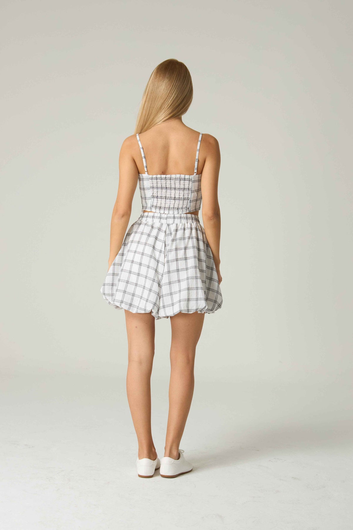 Woman wearing a checkered dress on a plain background.