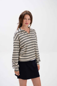 Woman wearing a black and white striped shirt with a black skirt on a white background.
