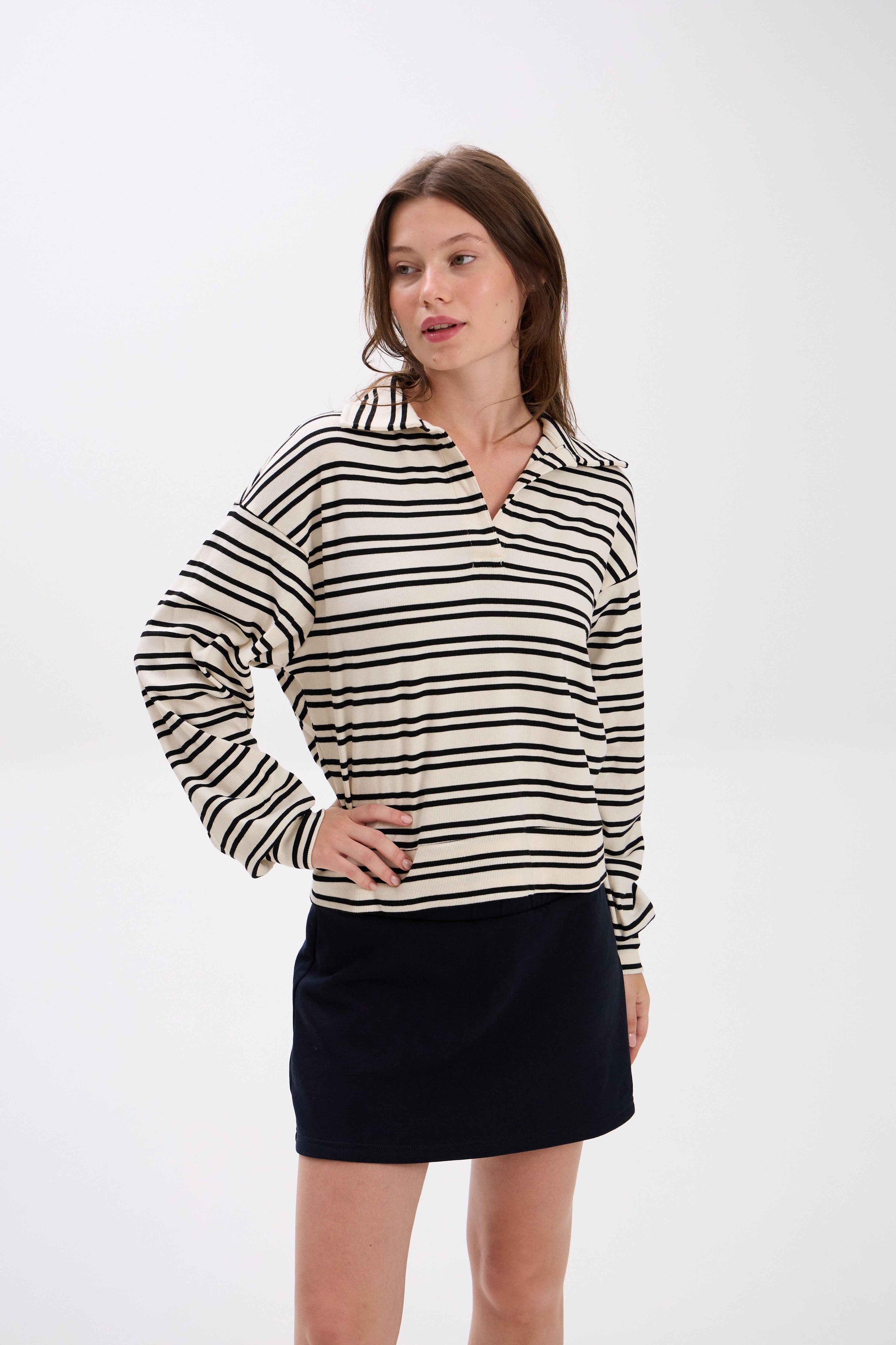 Woman wearing a black and white striped shirt with a black skirt on a white background.
