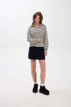 Woman wearing a striped sweater and black skirt on a white background.
