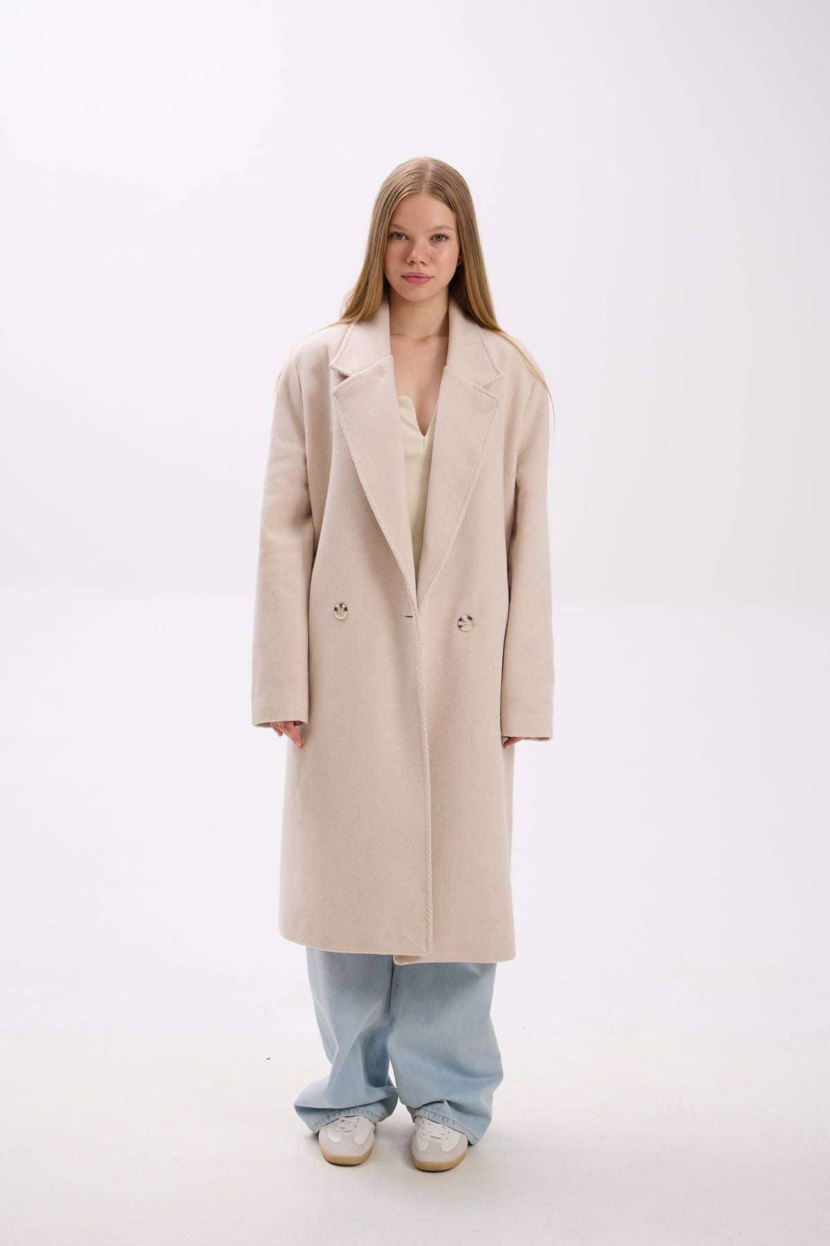 Person wearing a beige coat on a white background