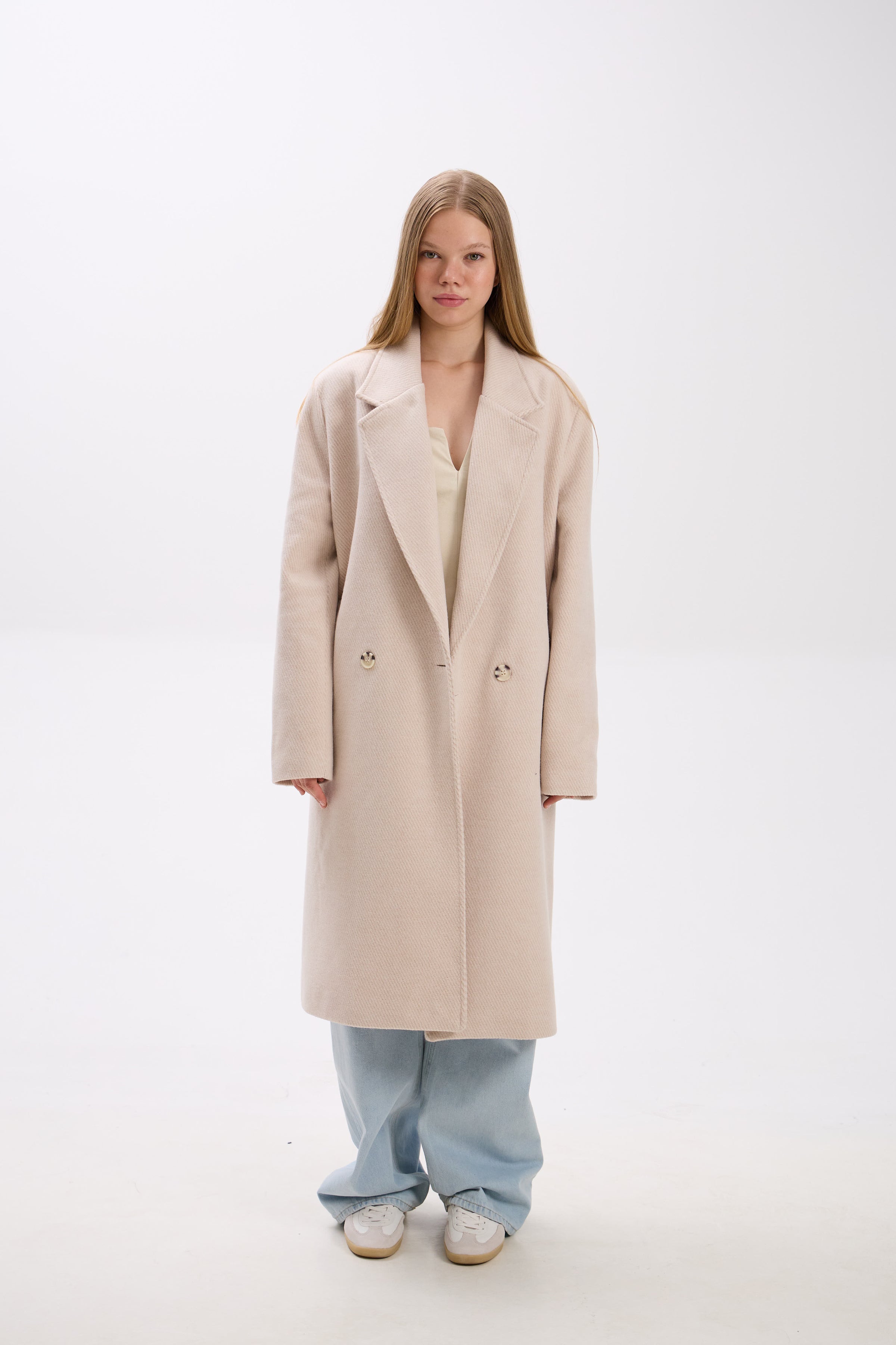 Person wearing a beige coat on a white background