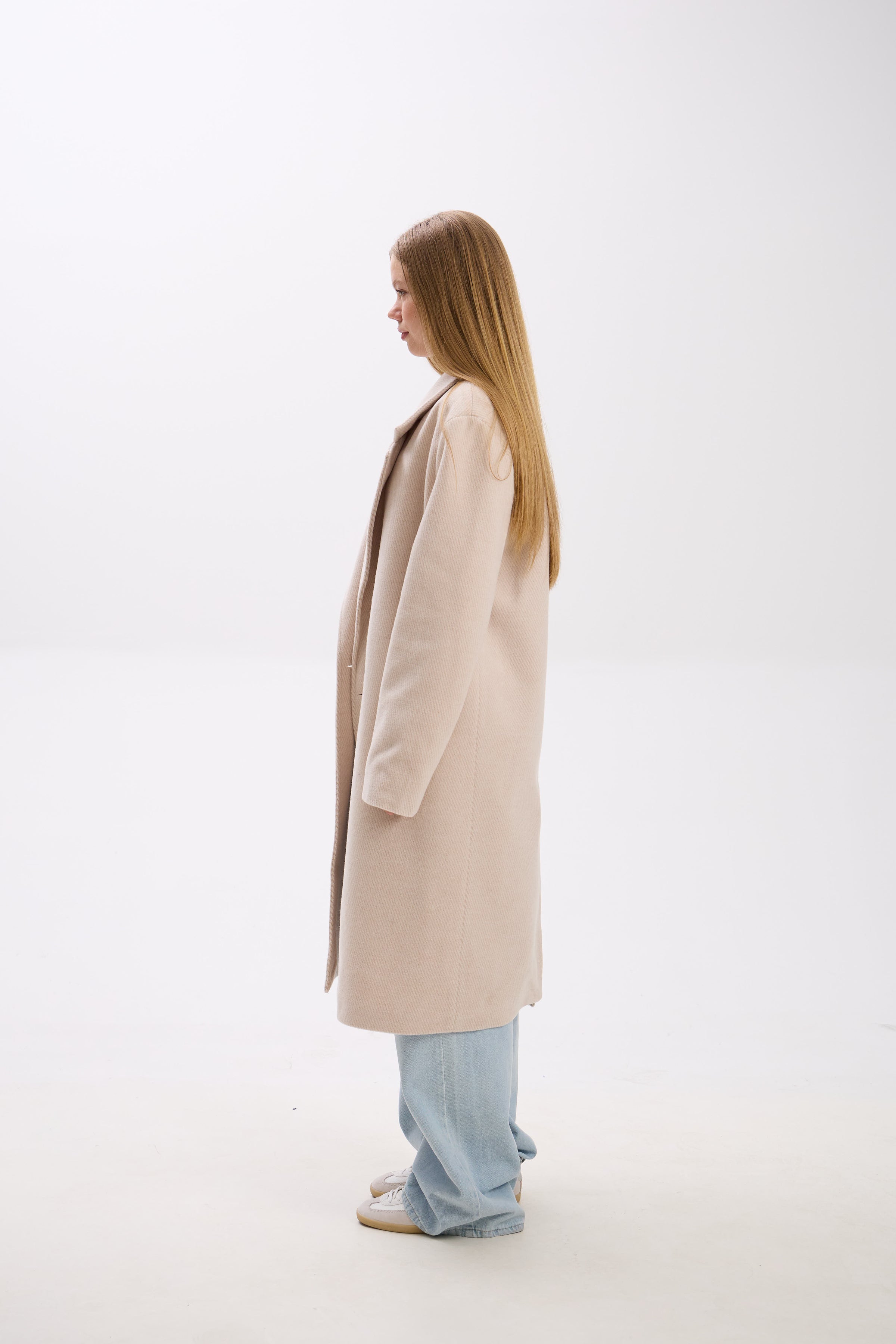 Person wearing a beige coat on a white background