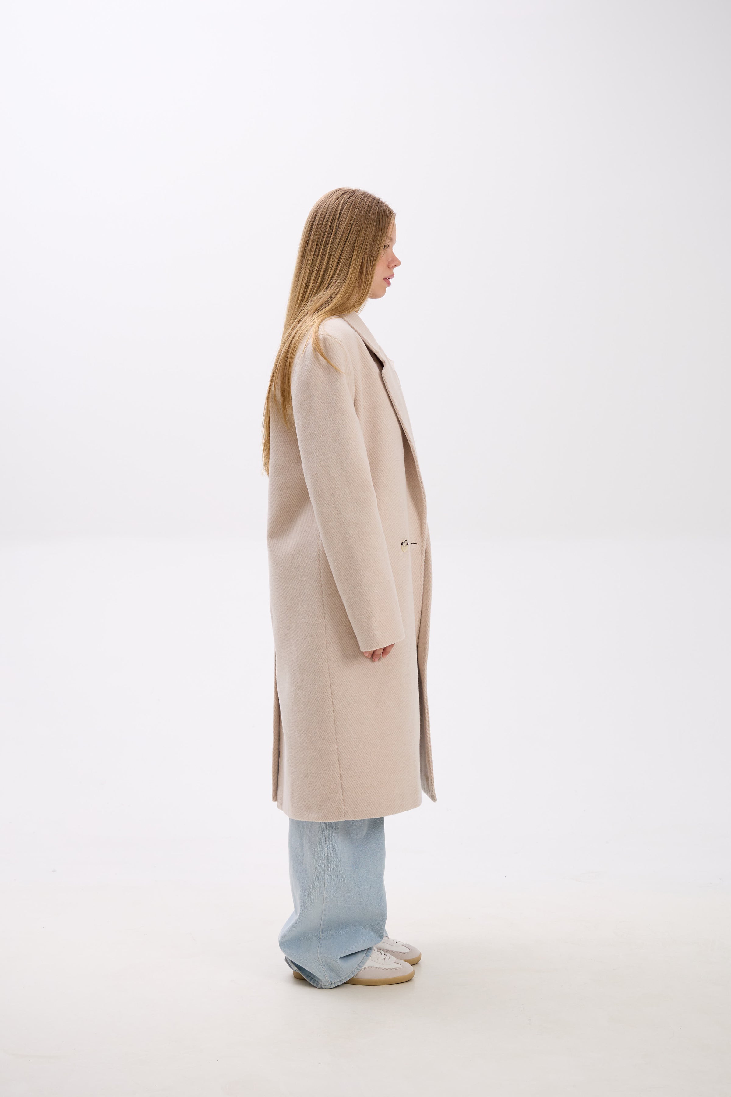 Person wearing a beige coat on a white background