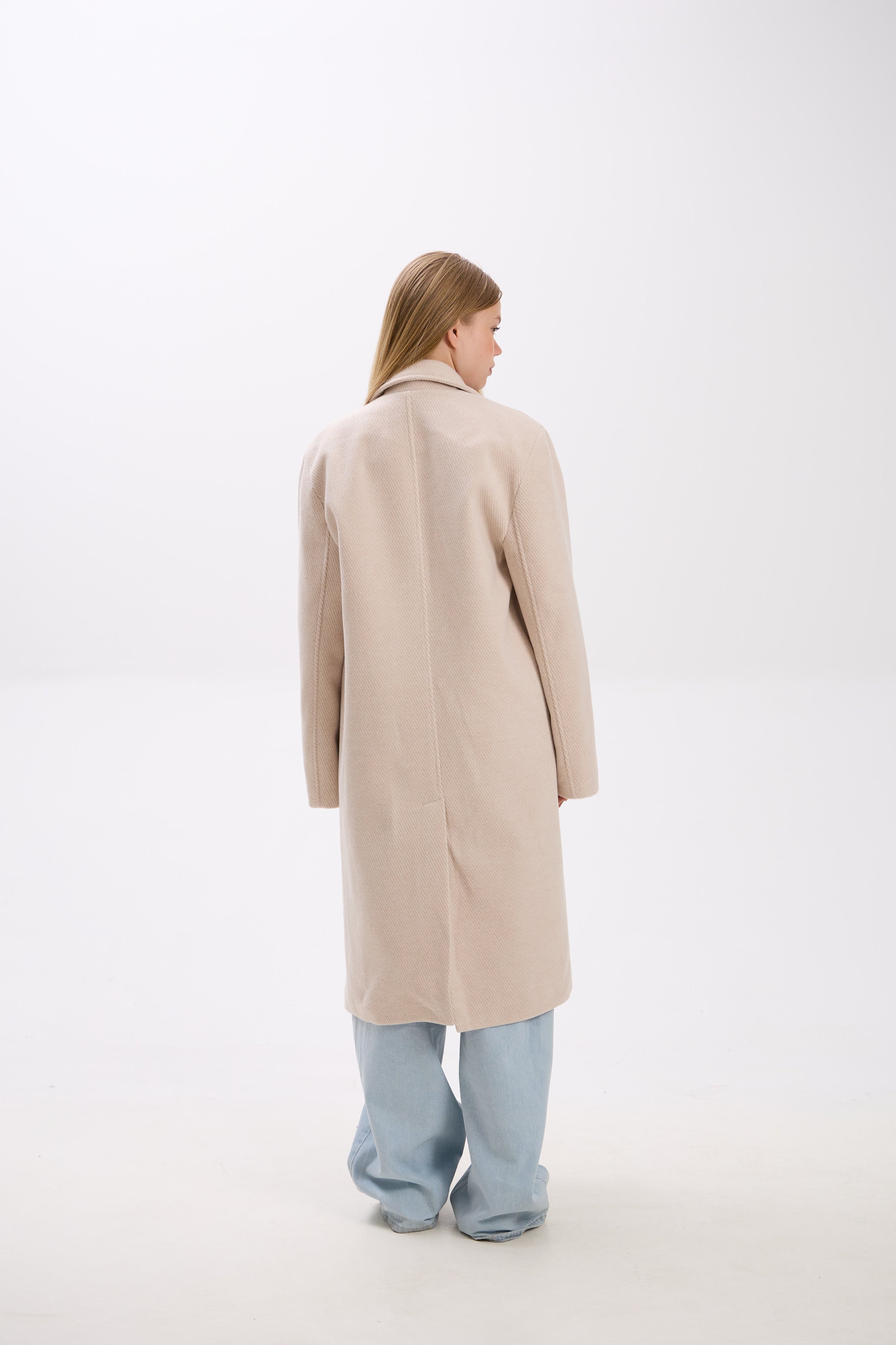 Person wearing a beige coat on a white background