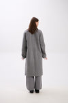 Person wearing a gray coat and pants on a white background