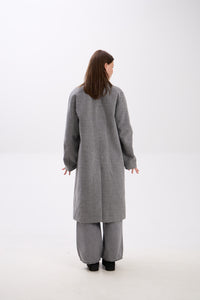 Person wearing a gray coat and pants on a white background