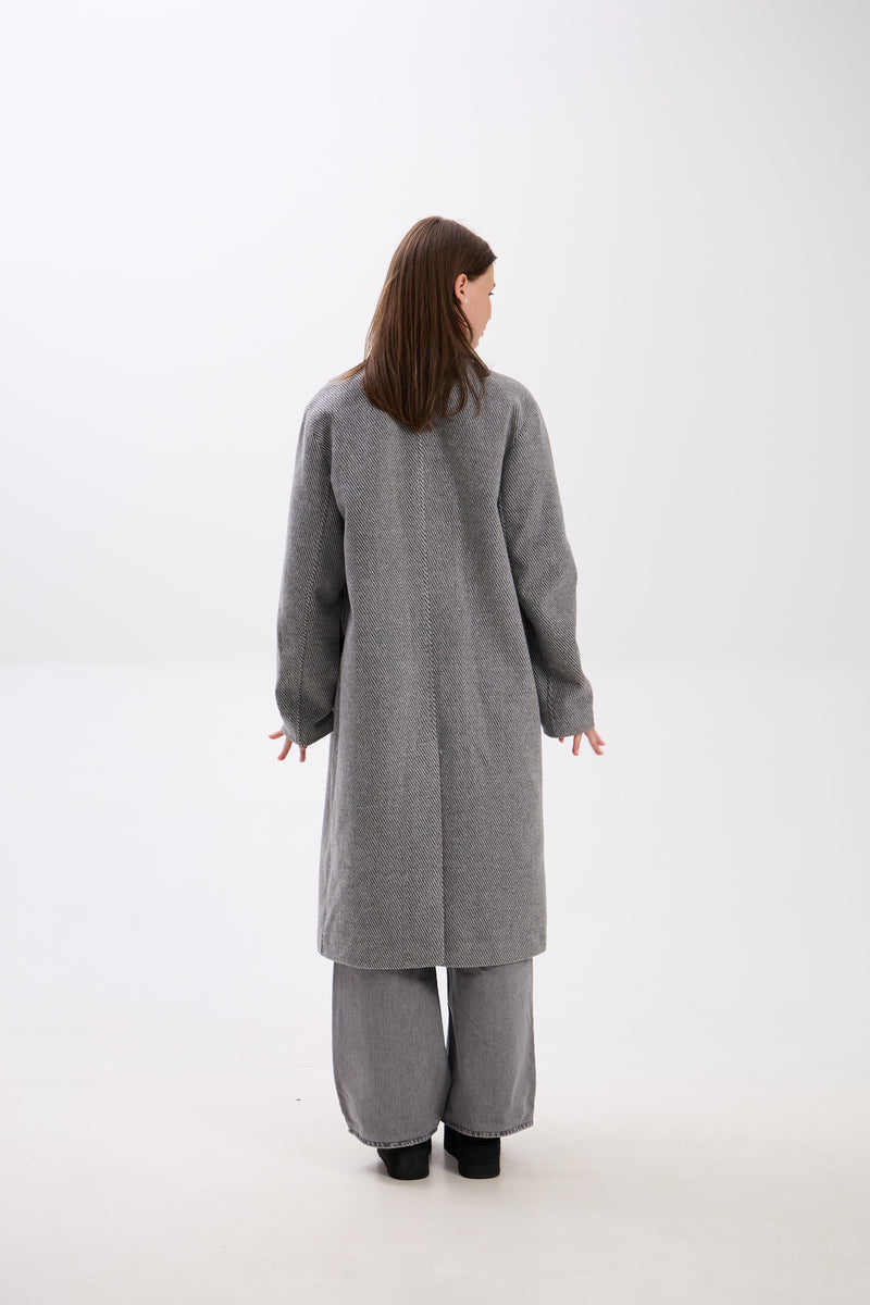 Person wearing a gray coat and pants on a white background