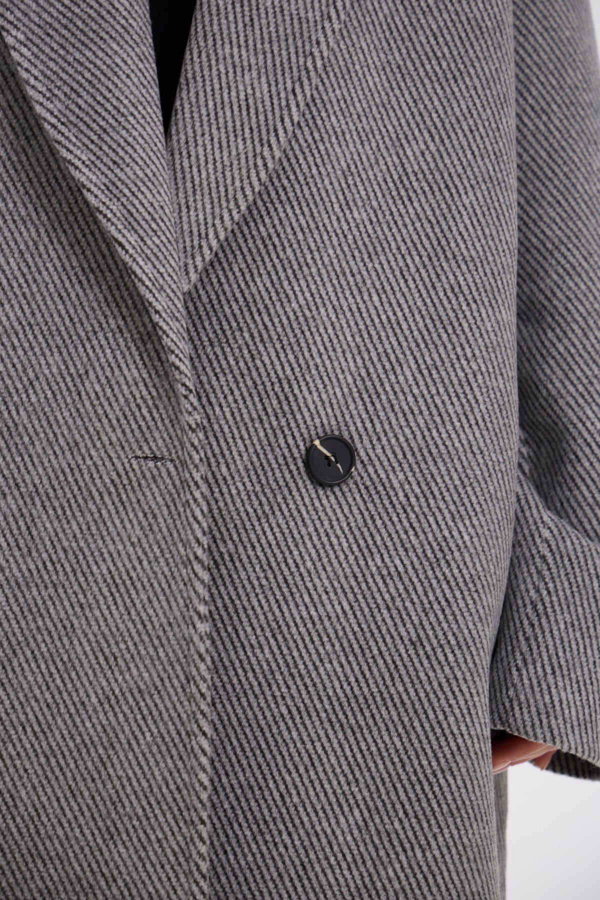 Close-up of a gray textured coat with a button on a white background