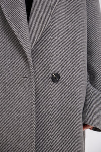 Close-up of a gray textured coat with a button on a white background