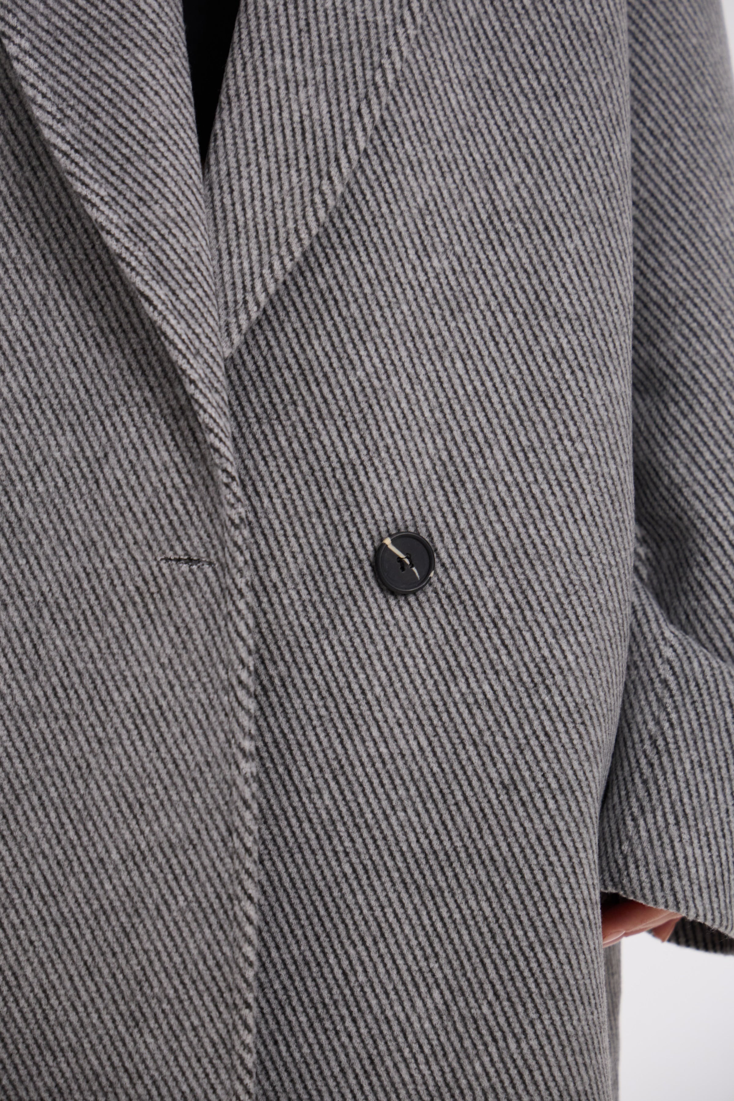 Close-up of a gray textured coat with a button on a white background
