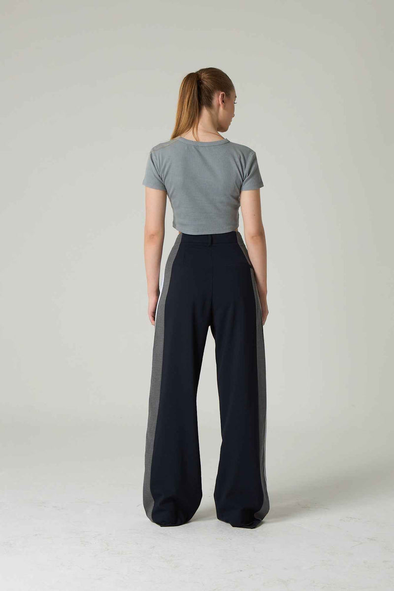 Person wearing a gray top and black high-waisted pants on a plain background.