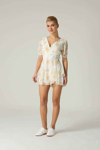 Woman wearing a floral dress on a plain background.