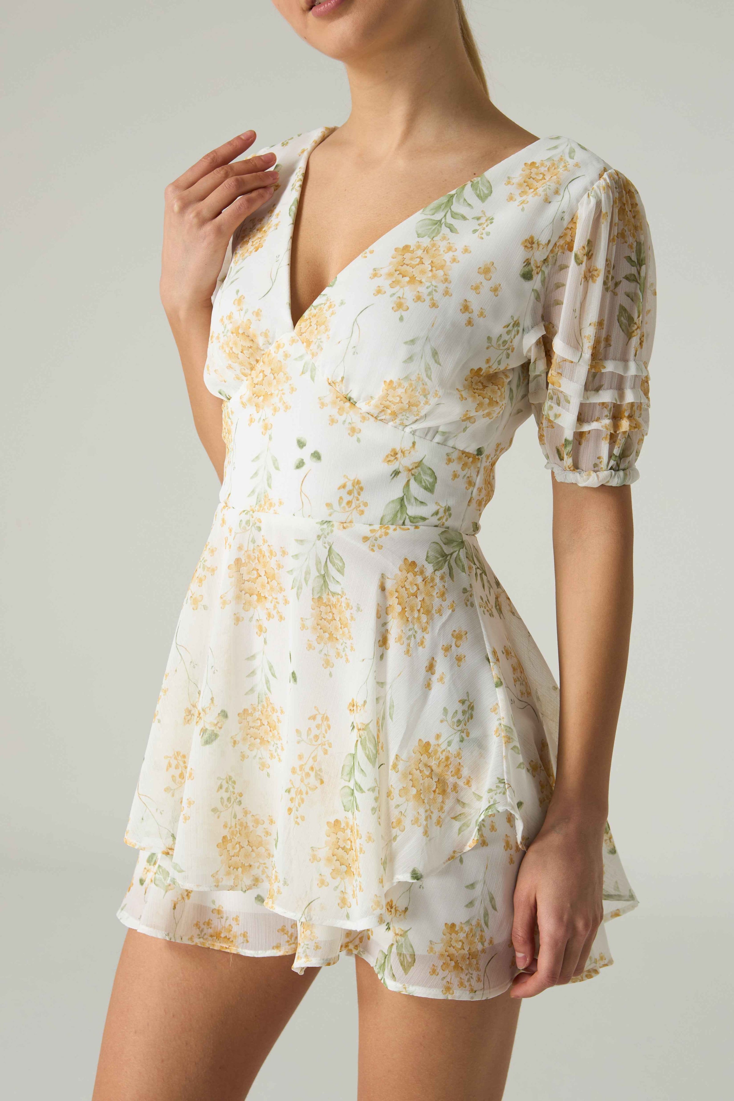 Woman wearing a floral dress with a plain background.