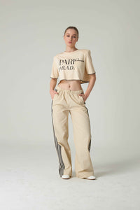 Person wearing a beige t-shirt and pants with stripes on a white background.