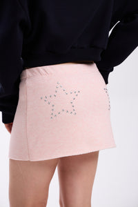 Pink skirt with star embellishments worn by a person on a white background.